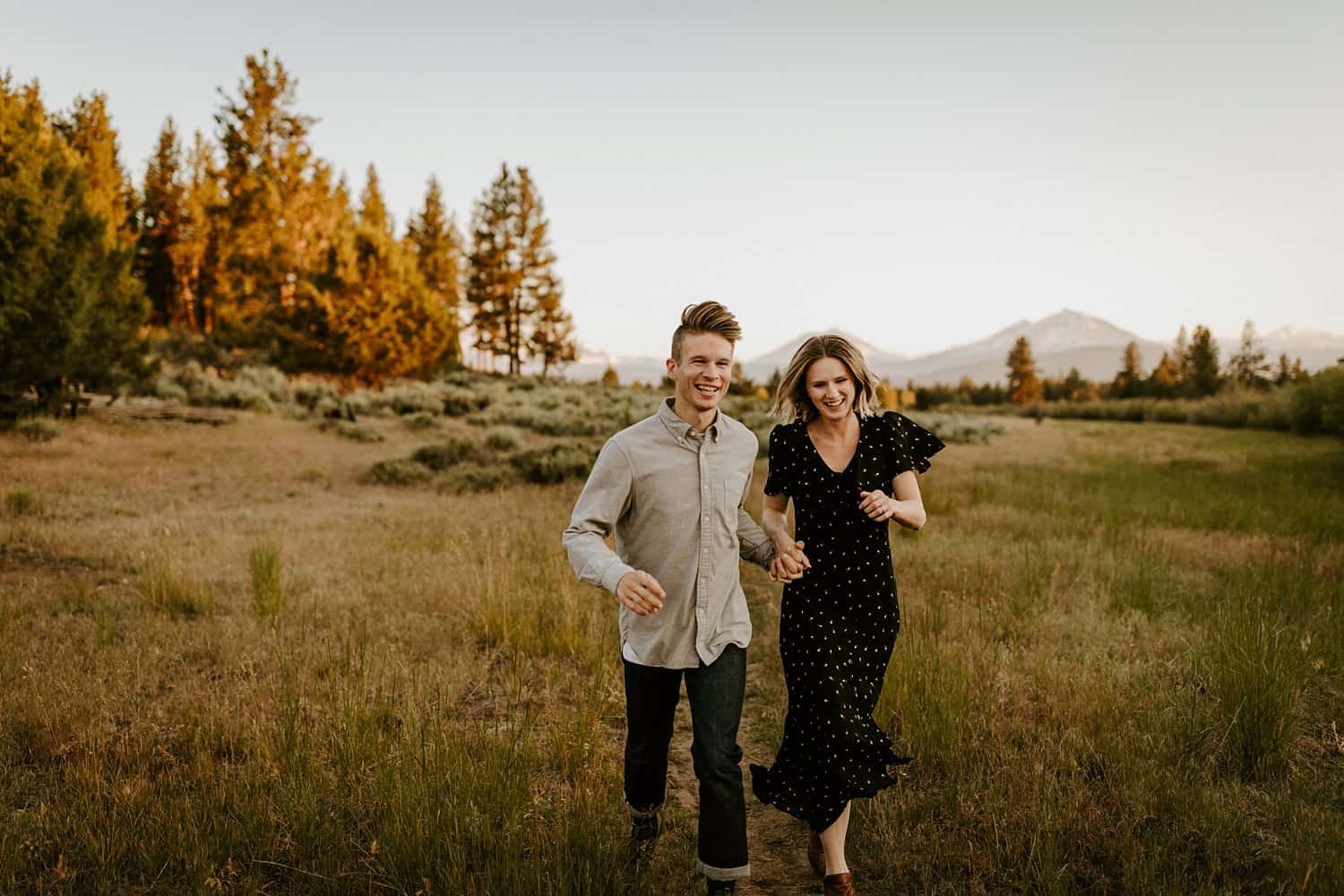Engaged couple in meadow in Central Oregon with a mountain view