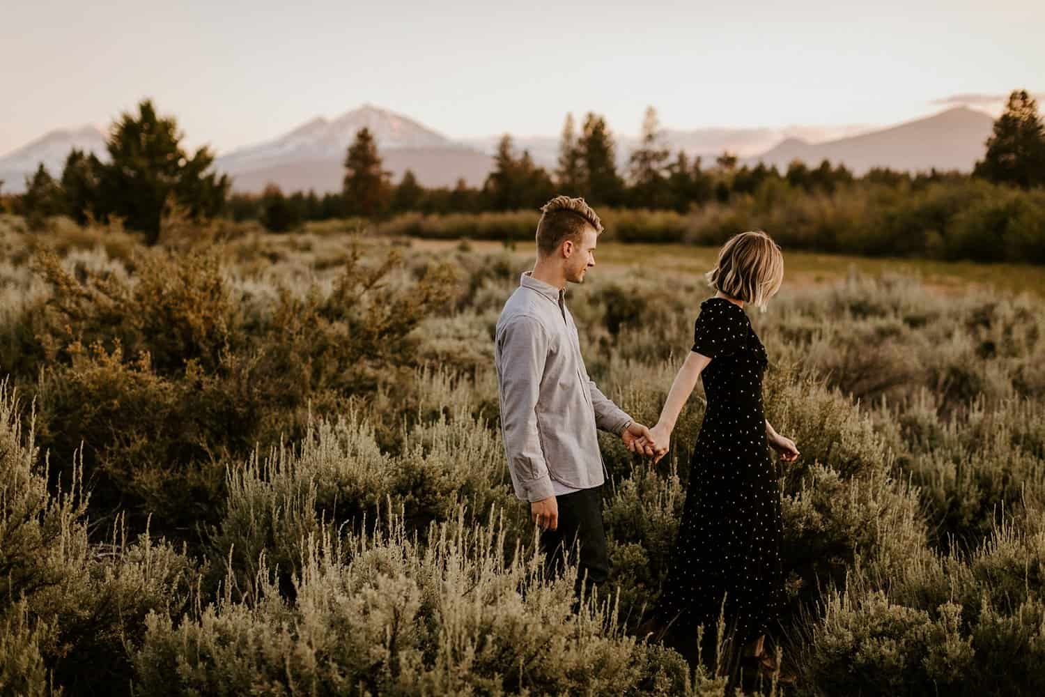 Engaged couple in meadow in Central Oregon with a mountain view