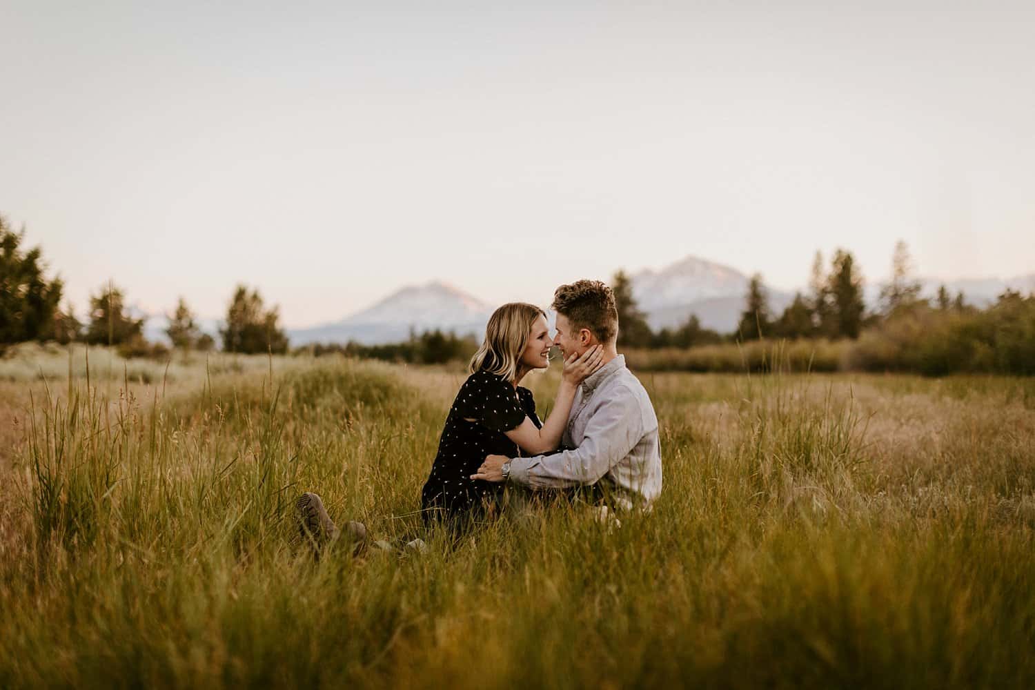 Engaged couple in meadow in Central Oregon with a mountain view